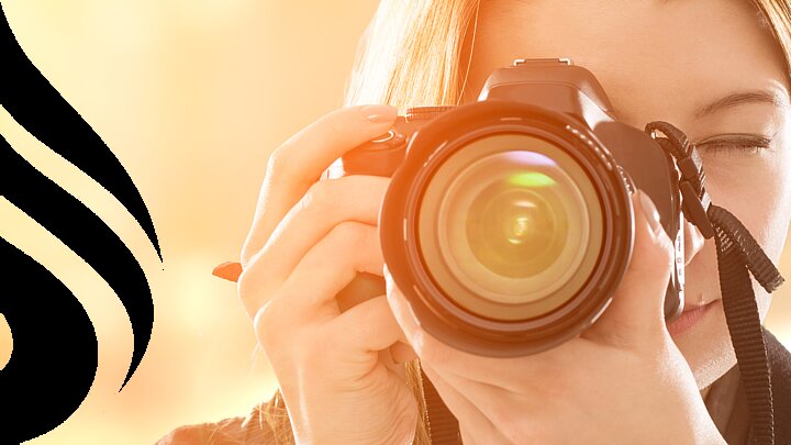 Kobieta trzymająca przy twarzy aparat forograficzny.