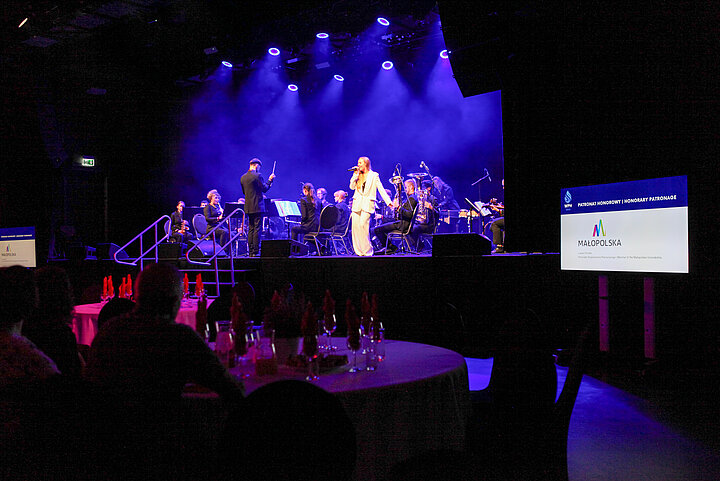 Na zdjęciu widać wnętrze klubu Studio, widać scenę, na której odbywa się koncert ORAGH, widać również stoliki z uczestnikami konferencji