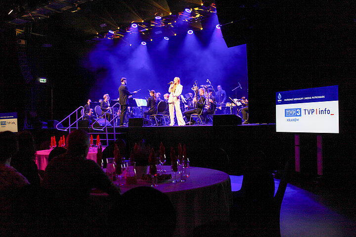 Na zdjęciu widać wnętrze klubu Studio, widać scenę, na której odbywa się koncert ORAGH, widać również stoliki z uczestnikami konferencji